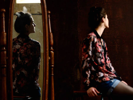 Femme de dos face à un miroir ancien, reflet et réalité qui se répondent, photographie par Laurent Hini