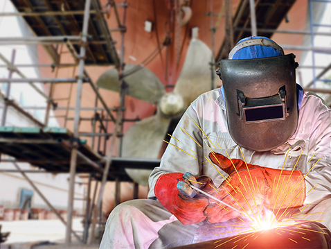 Person welding at shipyard