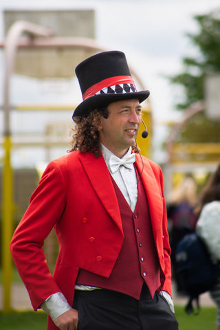 Man in red suit and top hat with microphone.
