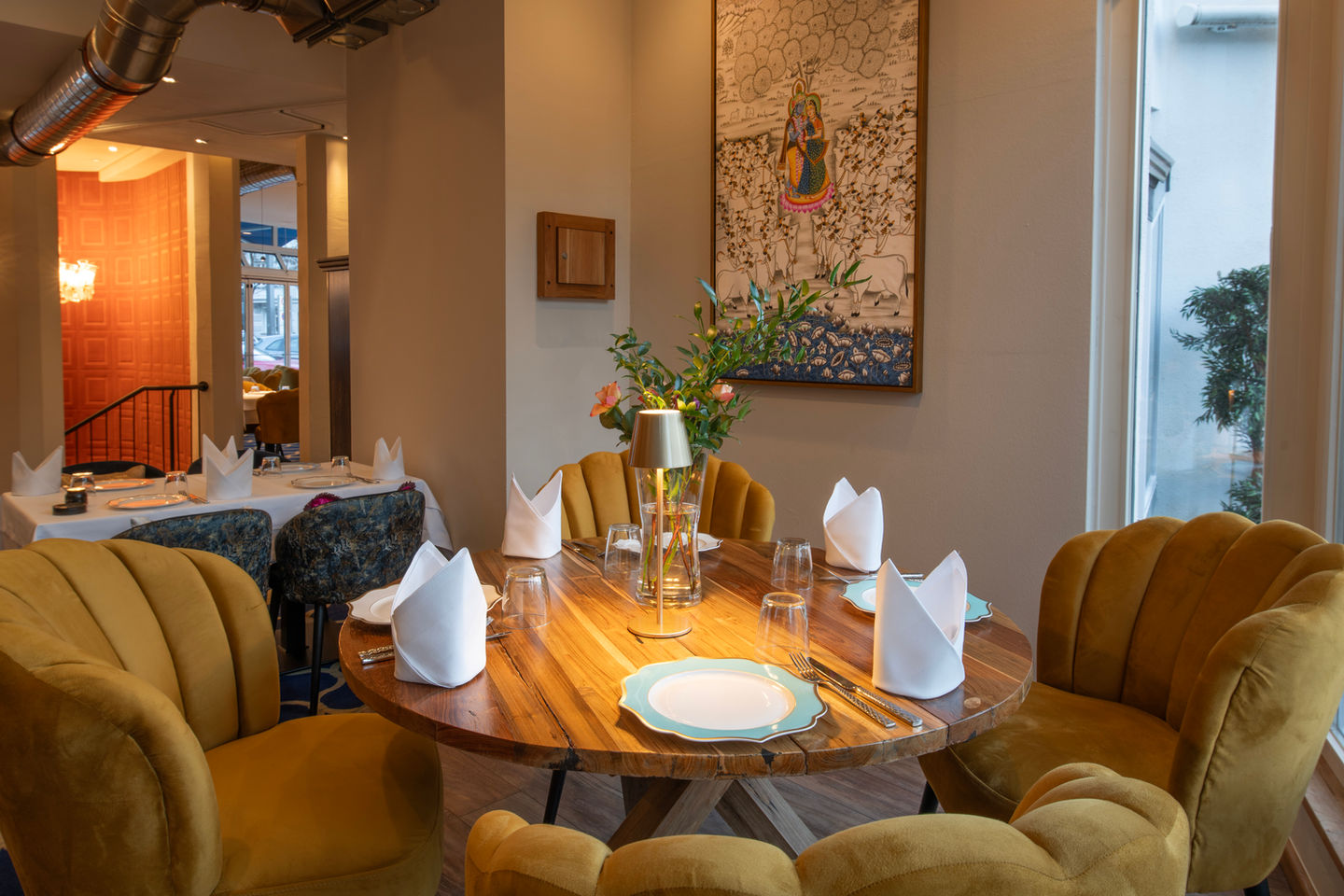 Set table for dining with yellow chairs, white napkins and flowers on a wooden table in The Indian Room