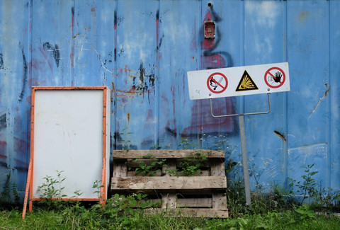 Warning sign for harmful substances in front of blue container