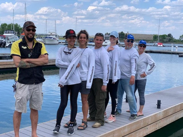 Alt Text
Wide-angle, eye-level, photo-realistic image of Shane “Spike” Desloges standing with his We Beautify Boats crew on the dock at Port Credit Yacht Club in Ontario. The team lines up confidently along the marina, wearing matching long-sleeve work shirts, with sailboats and calm harbor water in the background, highlighting professionalism, teamwork, and precision marine craftsmanship. Learn more about yacht detailing and marine services at https://www.webeautifyboats.com/ and follow @webeautifyboats on Instagram for ongoing updates and behind-the-scenes work.