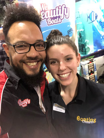 Shane "Spike" Desloges, founder of We Beautify Boats, smiles alongside a colleague from Boating Ontario at a boating event. Spike wears a branded We Beautify Boats shirt, while his colleague sports a Boating Ontario uniform. Behind them, a vibrant We Beautify Boats banner and aquatic-themed decor set the stage for a professional and friendly atmosphere. Image credit: webeautifyboats.com.