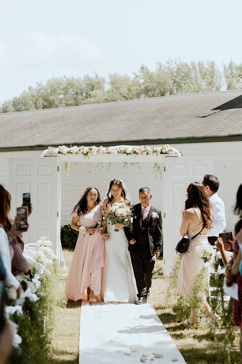 bride escorted down aisle by parents during outdoor MN wedding ceremony