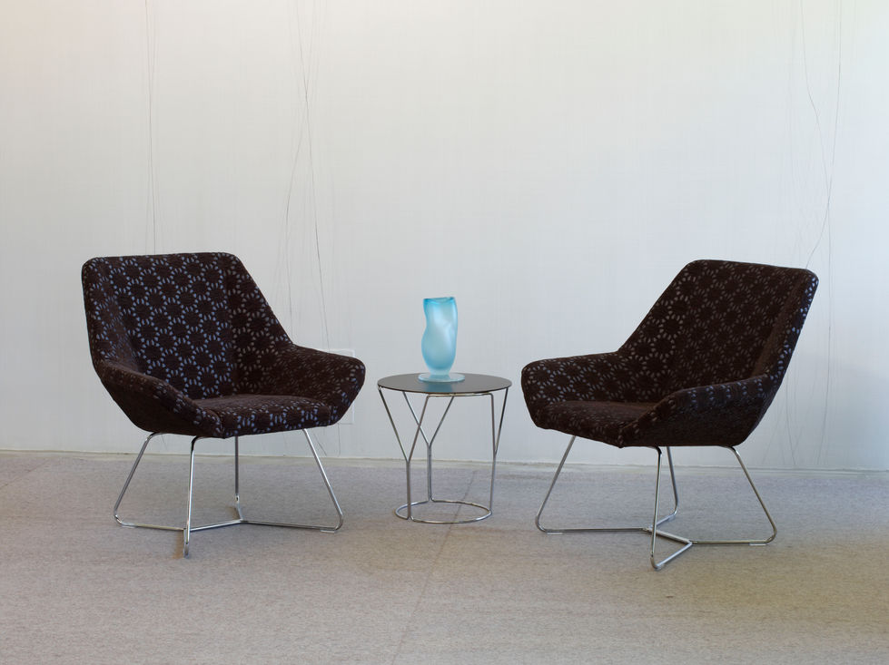 Two modern pattern chairs with a small side table.