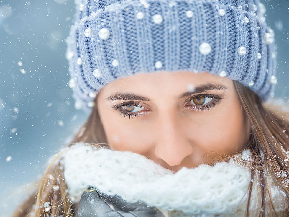 Photographie de portrait en extérieur d'une femme habillée chaudement ; des flocons de neiges tombent sur elle.