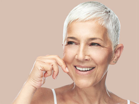 Photographie de portrait d'une femme mature se pinçant la joue mettant en valeur sa peau.