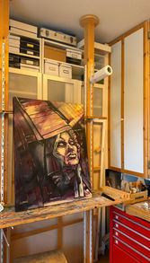 Das Originalwerk „Die Mutter (2022)“ steht auf einer Staffelei im Atelier von Carola E. Thiele. Die Umgebung mit Malwerkzeugen und Farbflecken dokumentiert die physische Entstehung des Unikats.