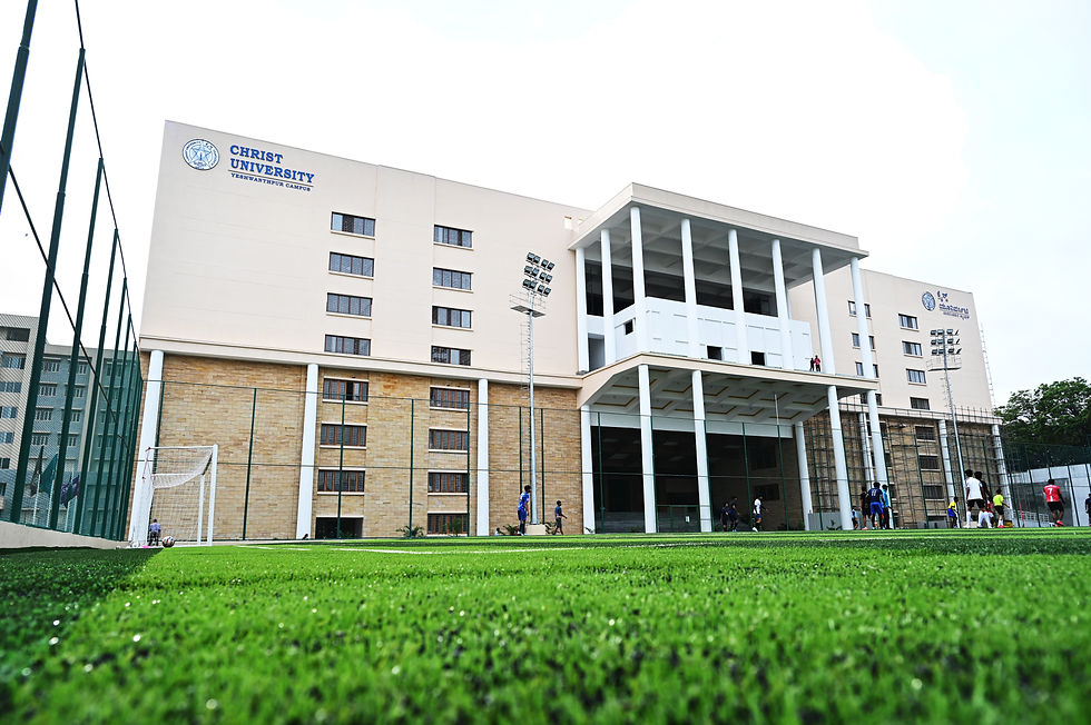 Exterior view of Christ University Yeshwanthpur Campus, showcasing its modern architecture and vibrant soccer field in use. Source citation: Suresh K Centre for Concept Design (CCD). (2023). BYC - Campus Photos . Google Drive.