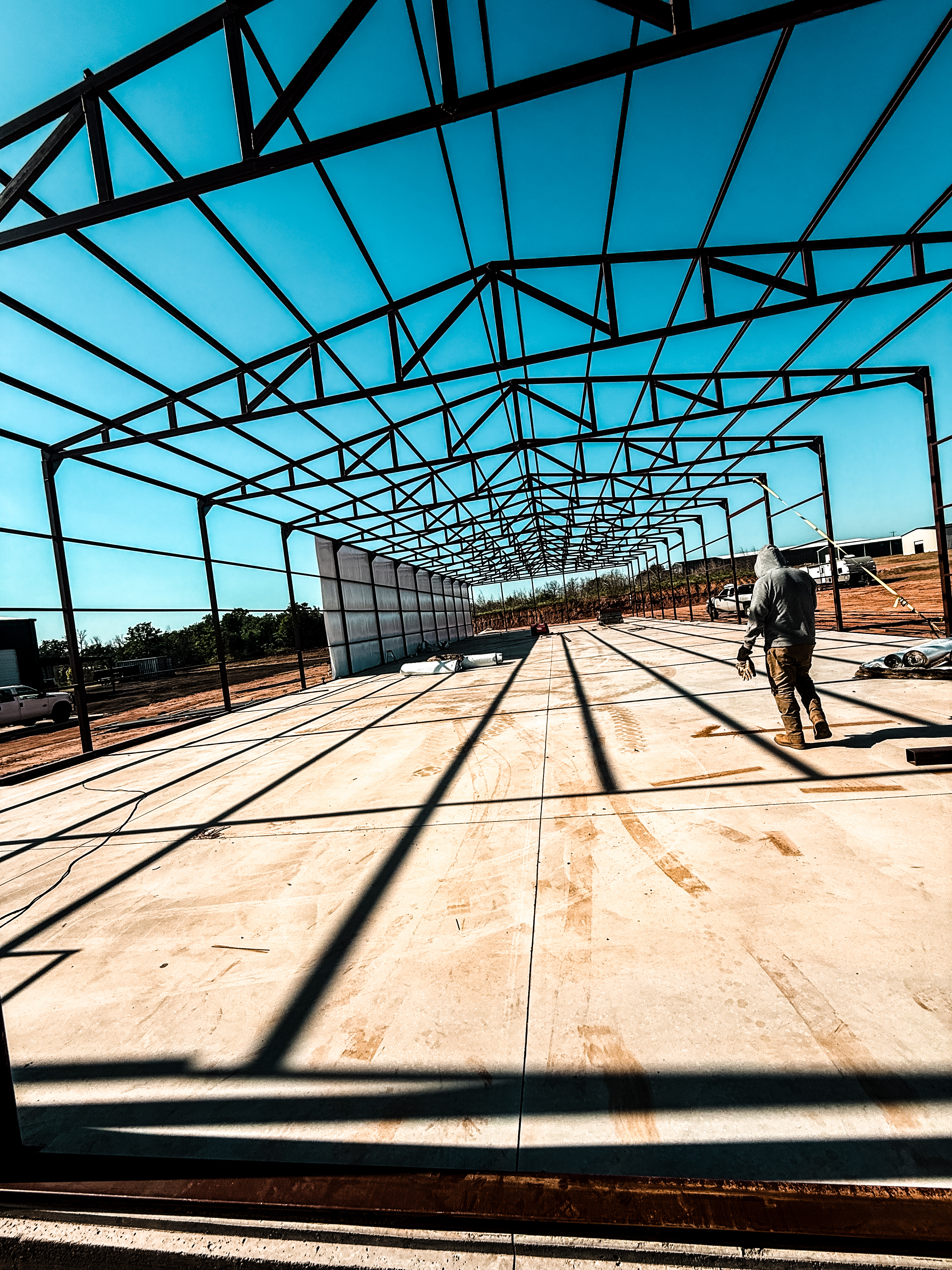Steel frame of a metal building going up over a concrete slab