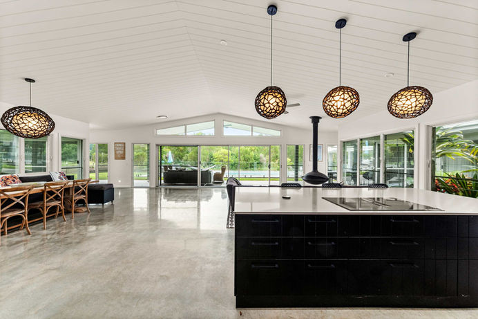 Huge open kitchen with hanging lights and polished floors with dark kitchen bench