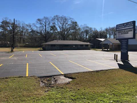 Freshly paved, sealed, and striped asphalt parking lot outside a commercial building in Louisiana, c