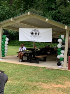 People sitting under the pavilion eating their food.