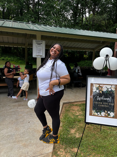A volunteer posing next to the welcome sign at the community outreach day.