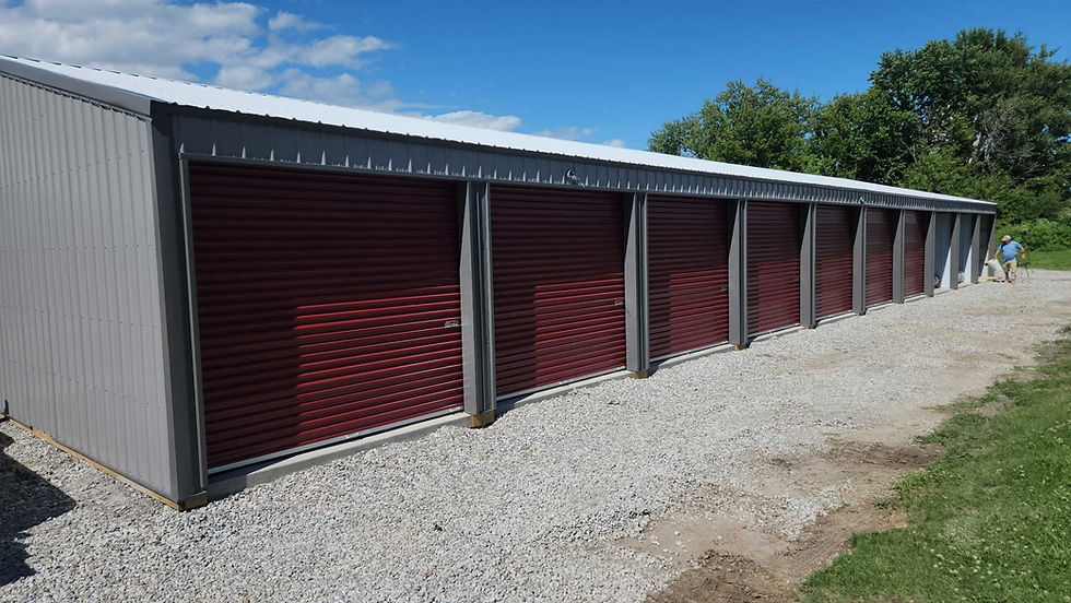 North side of a gray building with maroon roll up doors, recently constructed building with gravel driveway at North Main Mini-Storage in Sigourney, IA