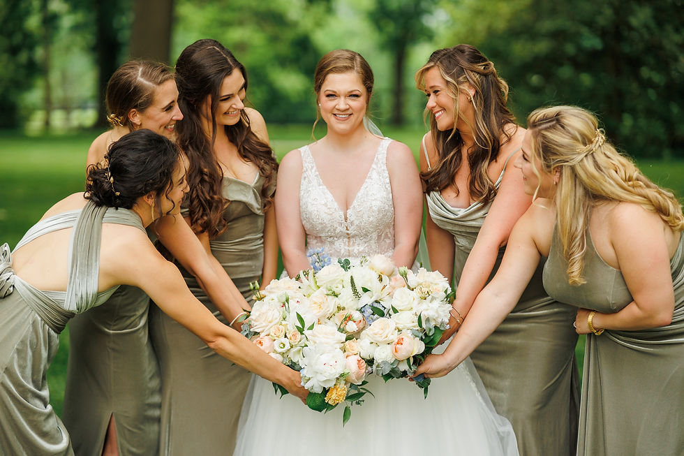 The bride faces the camera while her bridesmaids surround her, holding their bouquets together.