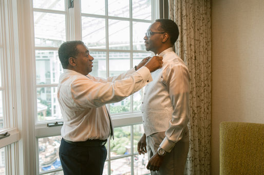 Groomsman fixes groom's tie.