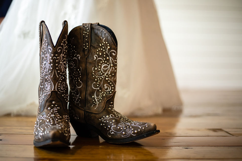 White embroidered bridal cowgirl boots with a wedding gown in the background.