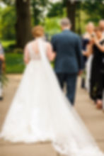 The back of the bride and her father as they walk down the aisle, her cathedral veil trailing behind her.