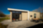 Two modern backyard guest houses with stucco exteriors and patio lighting