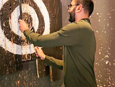A man in a green polo playing axe throwing