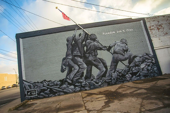 A stirring depiction of an iconic WWII photograph. Completing the patriotic theme, a pole extending above the mural presents the American flag and brings a unique movement to the artwork.