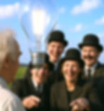 A team laughing and pointing at a big idea lightbulb floating in air with no wires they think is absurd.