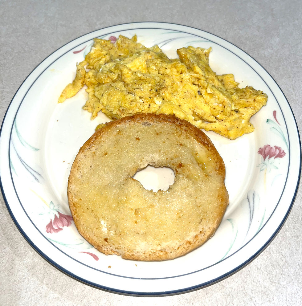 A breakfast plate with scrambled eggs and half a bagel.
