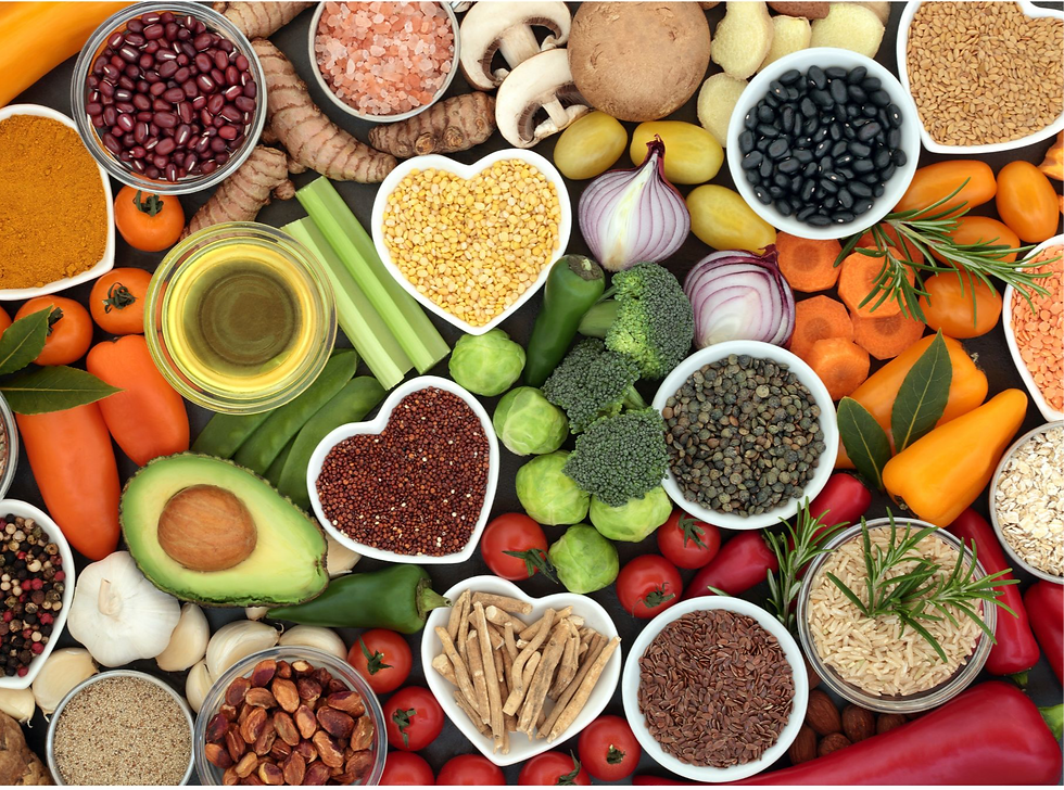An array of colorful vegetables, grains, and herbs, including avocados, peppers, and broccoli, arranged in bowls on a dark surface.