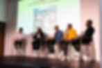 Five people having a discussion in front of a screen.
