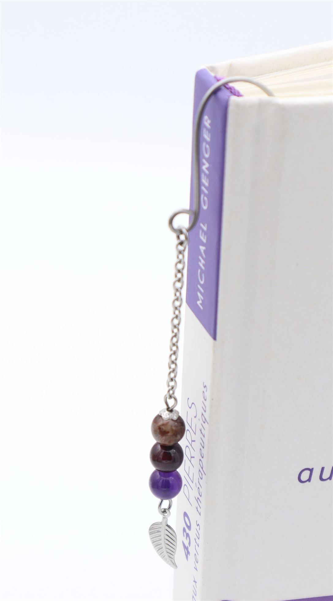 Marque pages bijoux  en acier inoxydable  avec des pierres semi précieuse d'améthyste, auralite et grenat avec une feuille exposé sur son livre