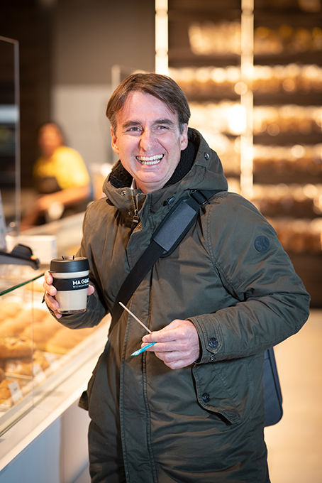 Lächelnder Mann mit Kaffeebecher in Bäckerei.