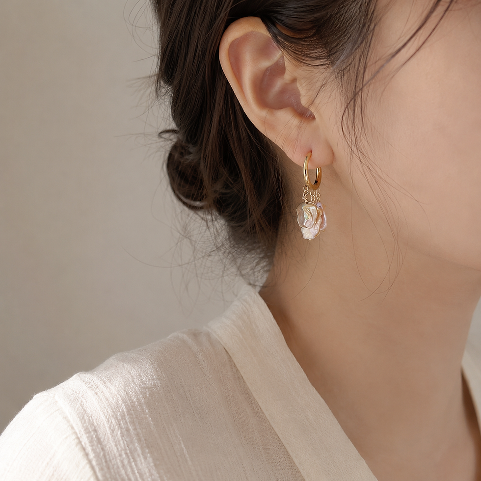 Keshi pearl drop earring with purple-gray iridescent tone on a gold titanium huggie hoop, worn on the ear