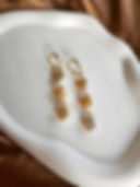 Golden Hour earrings laid on a white ceramic dish against warm brown silk.