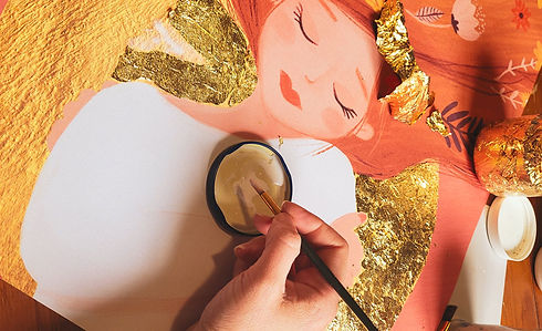 Photo de Nadia Bories en train de poser de la feuille d'or sur une de ses illustrations