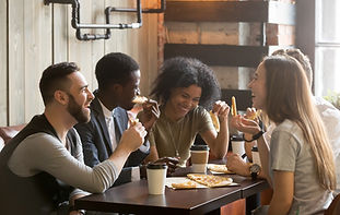 Multiracial happy young people eating pizza in pizzeria, black and white cheerful mates la
