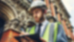 A surveyor outside a commercial property holding a clipboard and making notes for the rebuild cost assessment he is conducting.