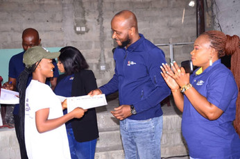 Afro Innovation Group team members presenting a certificate to a young woman during a community graduation event.