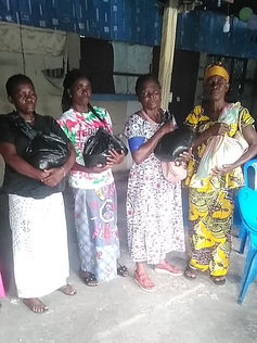 Four women holding bags of goods pose for a photo with a smile.
