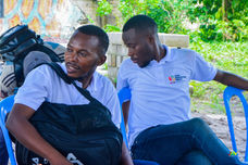 Two Afro Innovation Group team members sitting outdoors in discussion during a community engagement session.