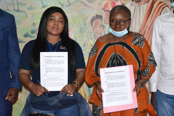 Two Afro Innovation Group representatives standing with a community partner holding signed collaboration agreements.