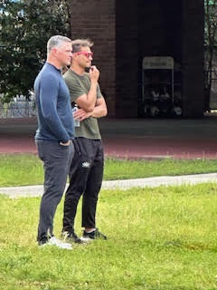 two men stand on grass