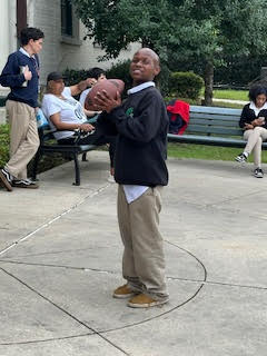 a child holds a football while standing on concrete