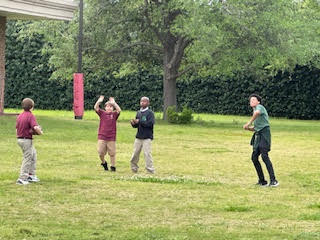 four children in a grassy field looking to catch a ball