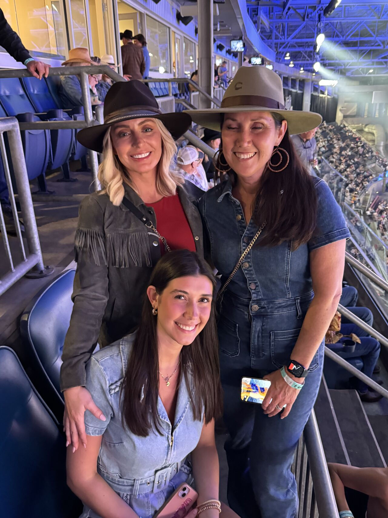 three women smiling at the camera in an arena