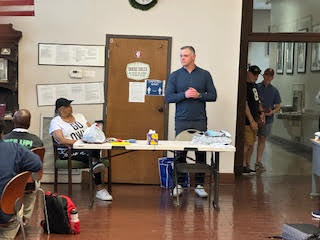a man stands at a table while a woman sits at the same table