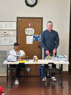 a man stands at a table while a woman sits at the same table