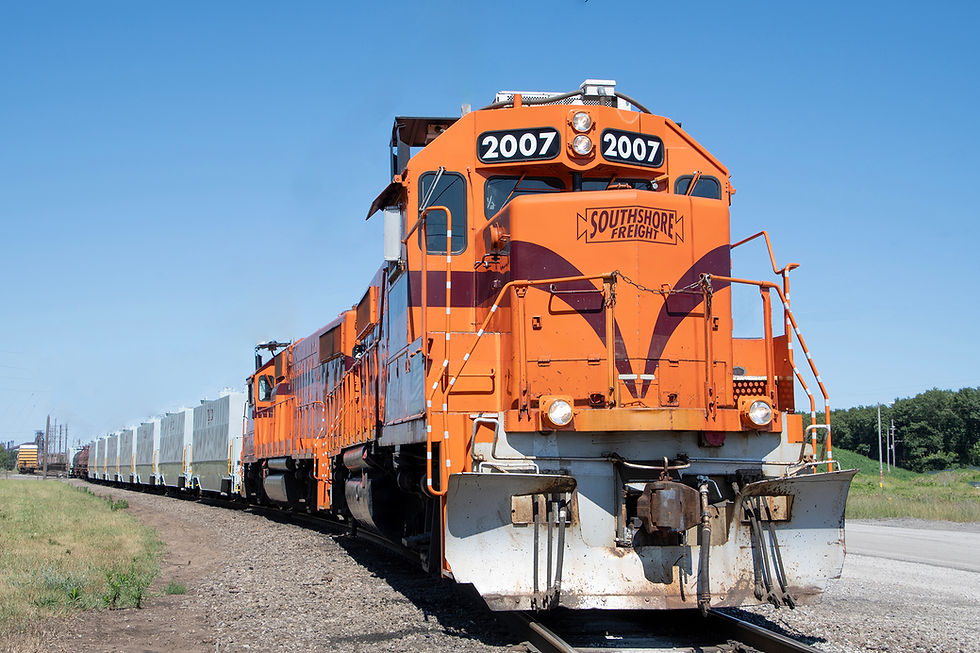 Orange train labeled "Southshore Freight" on tracks under a clear blue sky. It stretches into the distance, showcasing open countryside.
