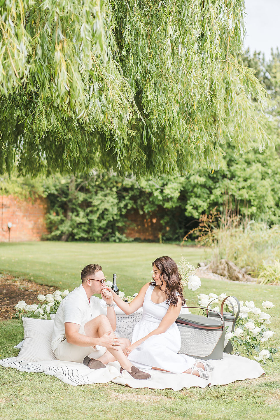 A couple enjoying a picnic under a willow tree surrounded by an arc of roses arranaged by Jacqui Owen of Jacqui O  