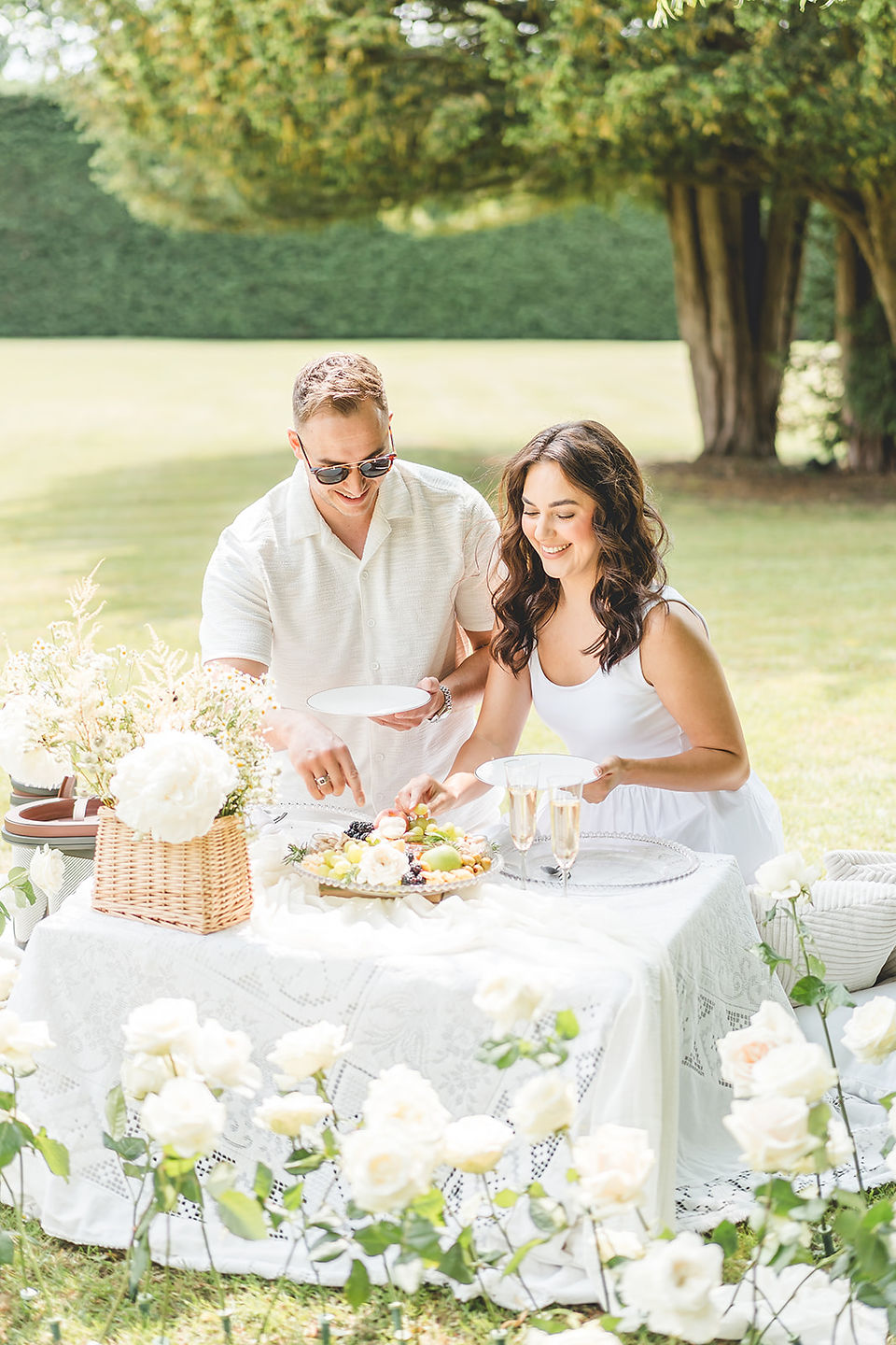 A couple enjoying a picnic under a willow tree surrounded by an arc of roses arranaged by Jacqui Owen of Jacqui O  